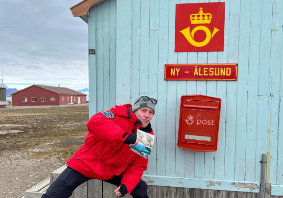 Ein Gast der Kreuzfahrt wirft eine Postkarte in Ny-Ålesund in den nördlichsten Briefkasten der Welt